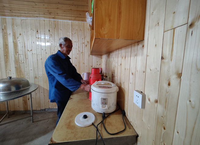 杉板裝飾的屋內,老黨員正熱情地給客人們倒茶。徐俊聰攝